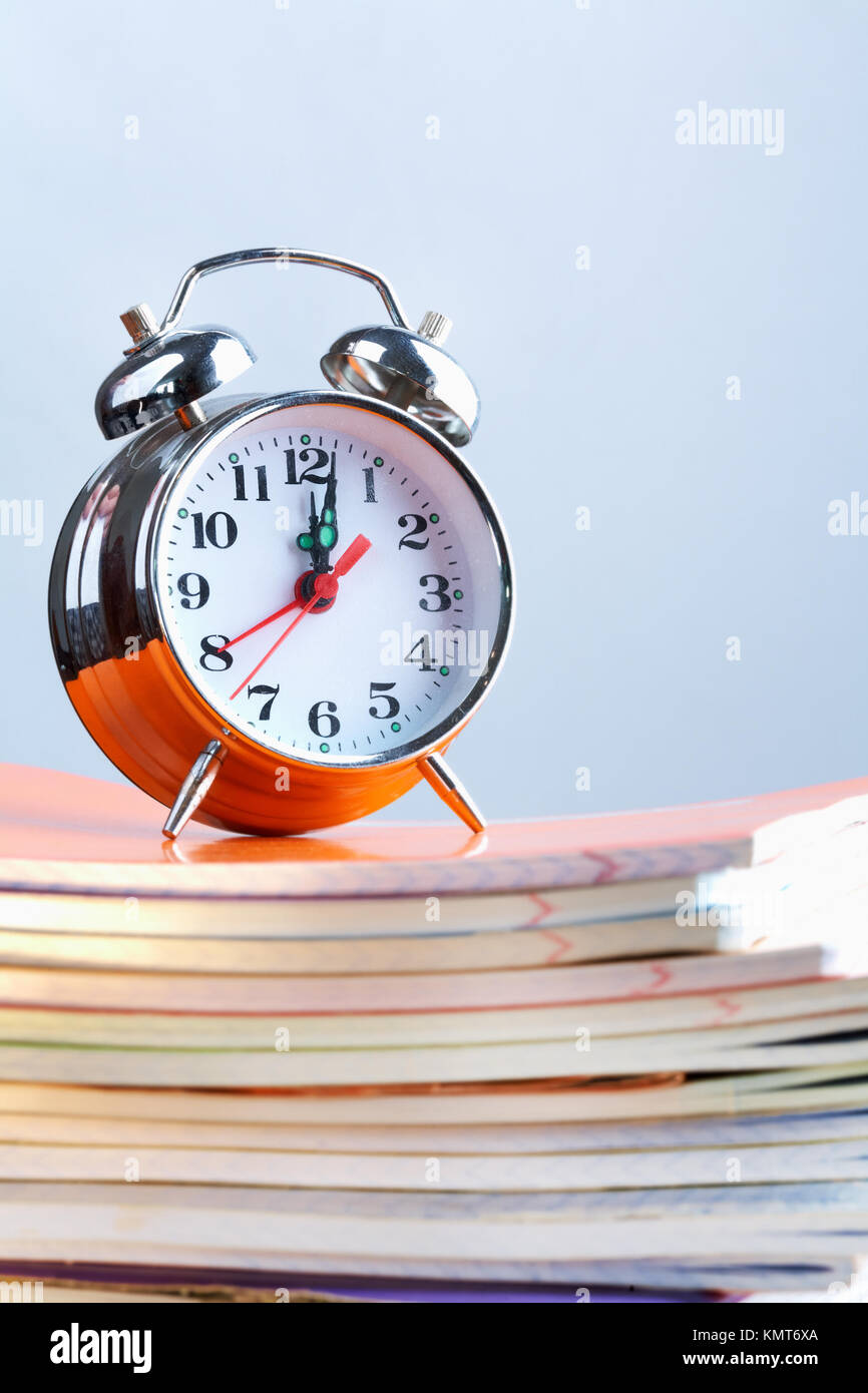 Stack of copybooks with alarm clock on its top Stock Photo