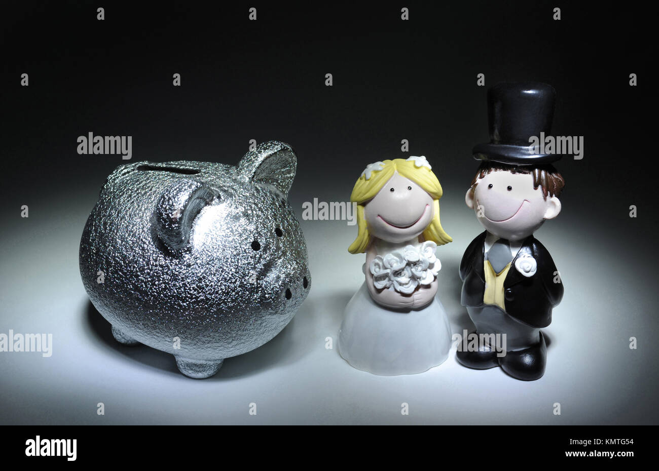 BRIDE AND GROOM FIGURES WITH PIGGYBANK RE WEDDING COSTS MARRIAGE DIVORCE PLANNING SAVING UK Stock Photo