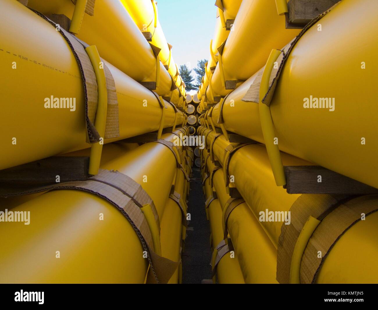 a stack of yellow natural gas utility pipes in a utility company yard