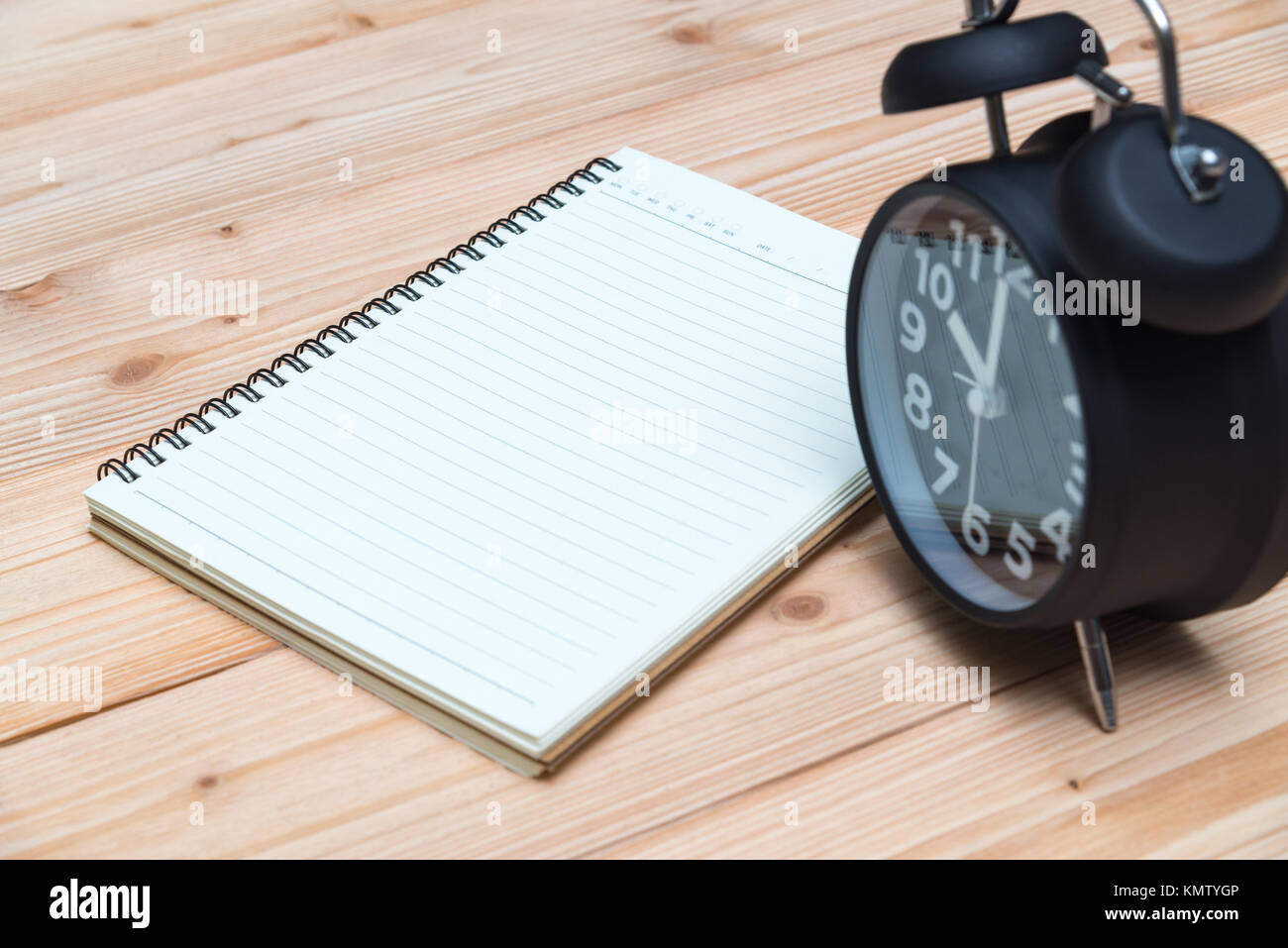 Vintage alarm clock and notebook with pen on wooden floor, empty space ...