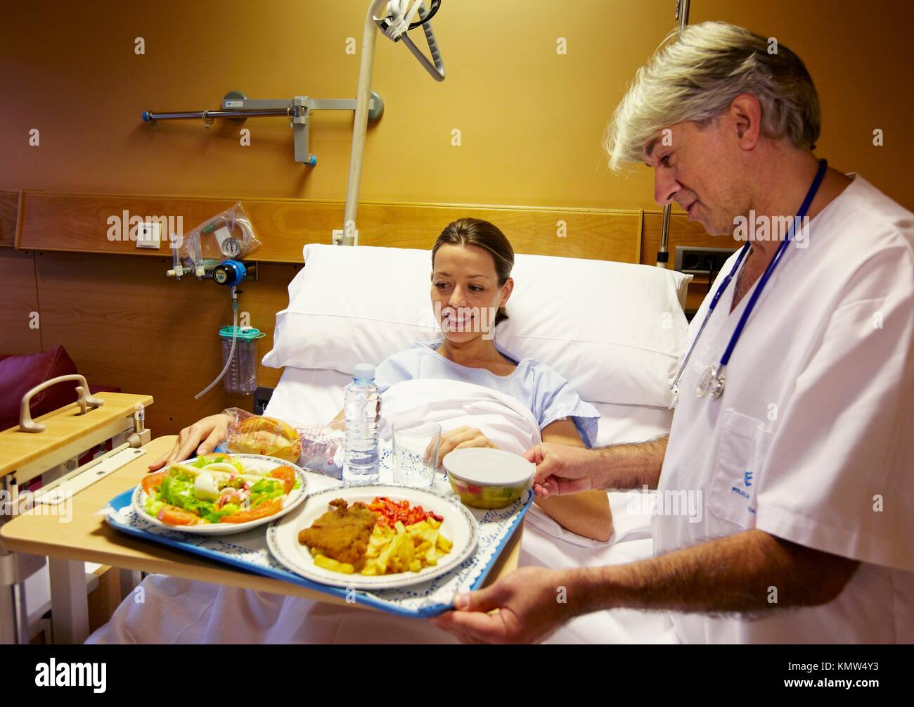 Nurse with food tray and patient in a hospital room. Hospital