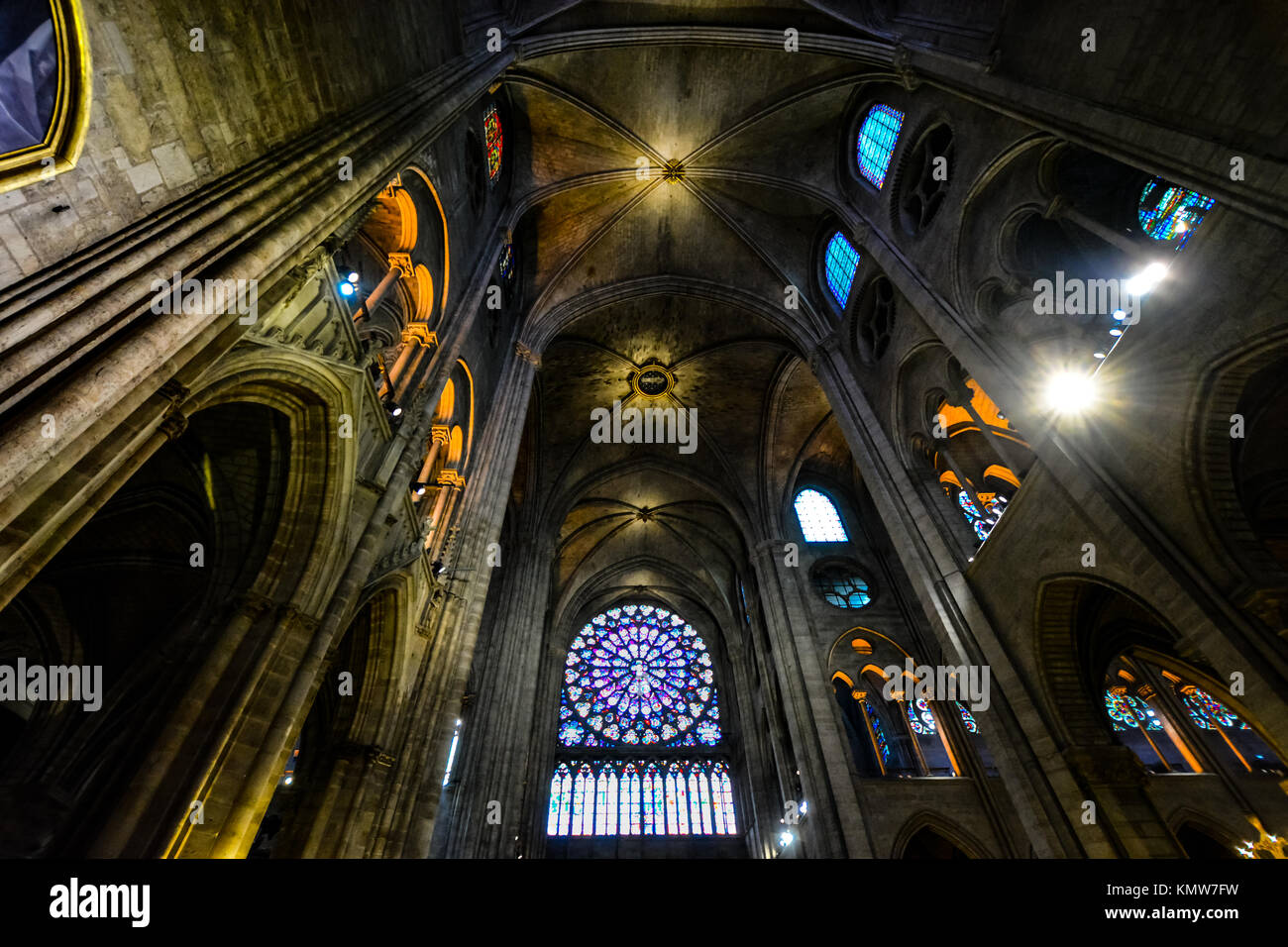 The interior of Notre Dame Cathedral in Paris France showing the rose window and other smaller stained glass windows highlighted by dramatic lighting Stock Photo