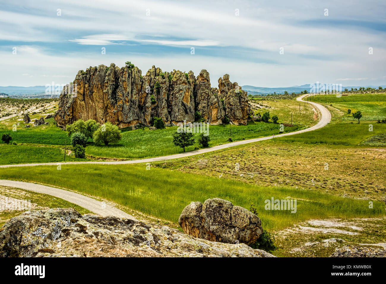 Road winding in green landscape under blue sky with white fluffy clouds ...