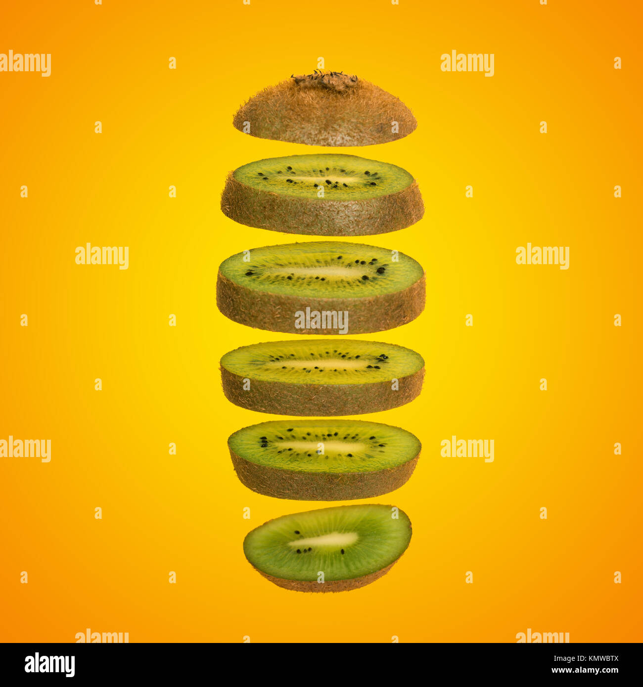 Creative concept with flying kiwi. Sliced kiwi isolated on yellow background. Levity fruit floating in the air Stock Photo