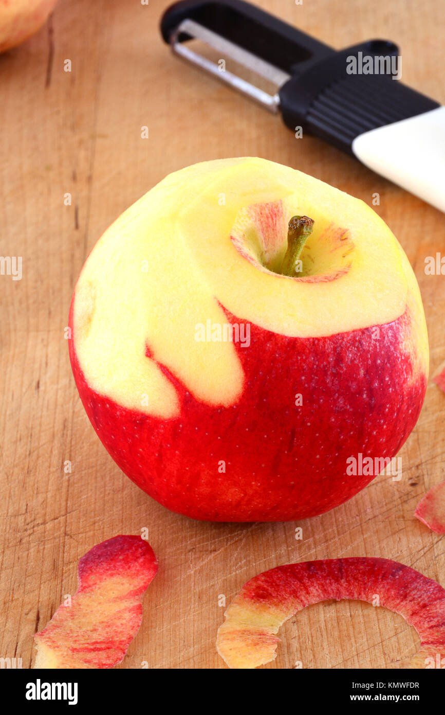Gala apple with peeler in vertical format.  Selective focus on top of apple.  Shot in natural light. Stock Photo