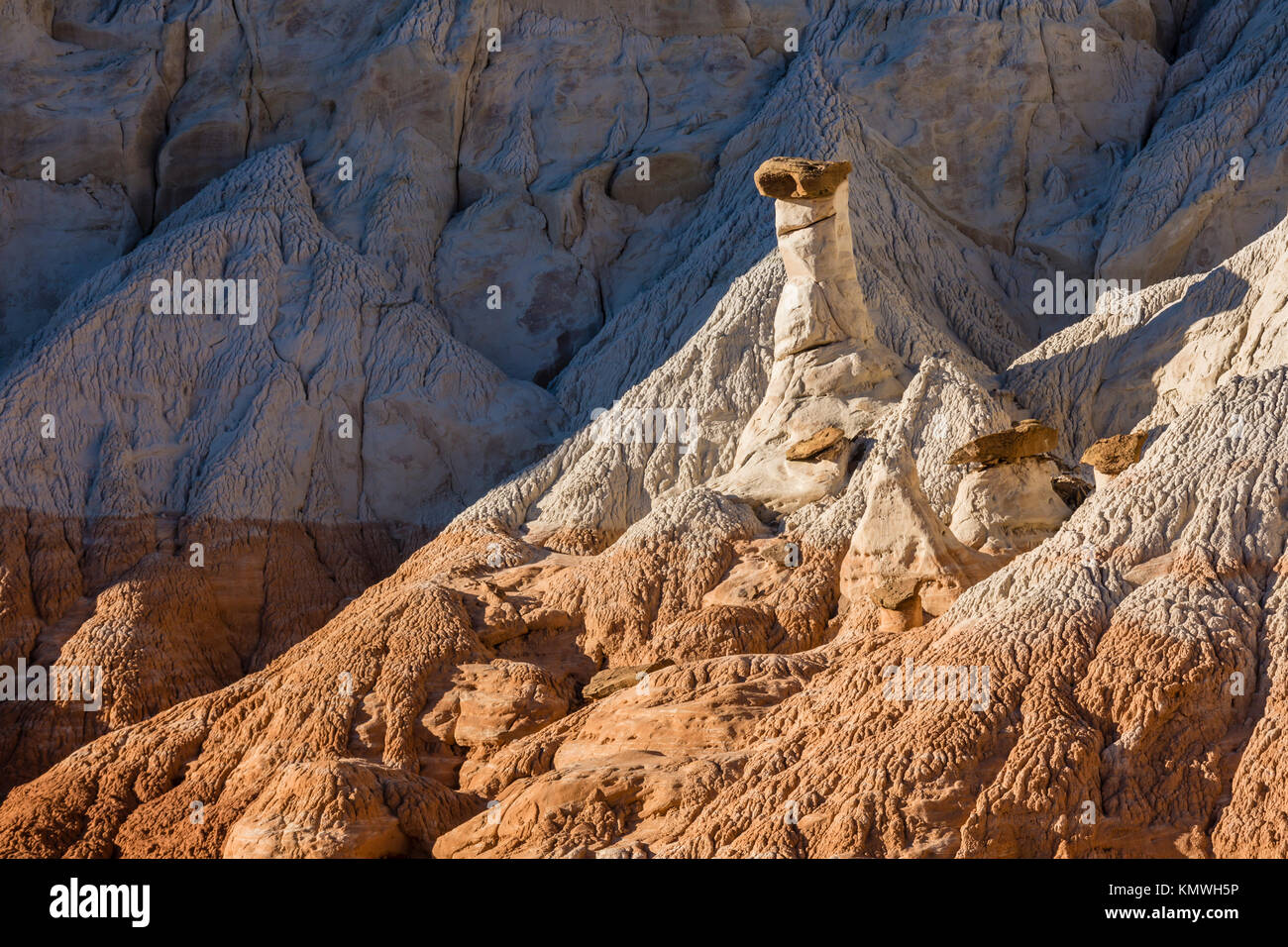 Toadstool Hoodoos hiding amongst the white and chocolate cliff layers of the Grand Staircase in Grand Staircase-Escalante National Monument near Kanab Stock Photo