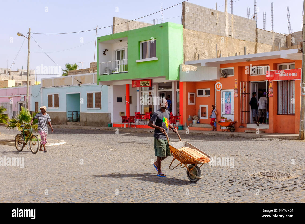 Street scene of a worker pushing a wheelbarrow, back street, Santa Maria, Sal, Salina, Cape Verde, Africa Stock Photo