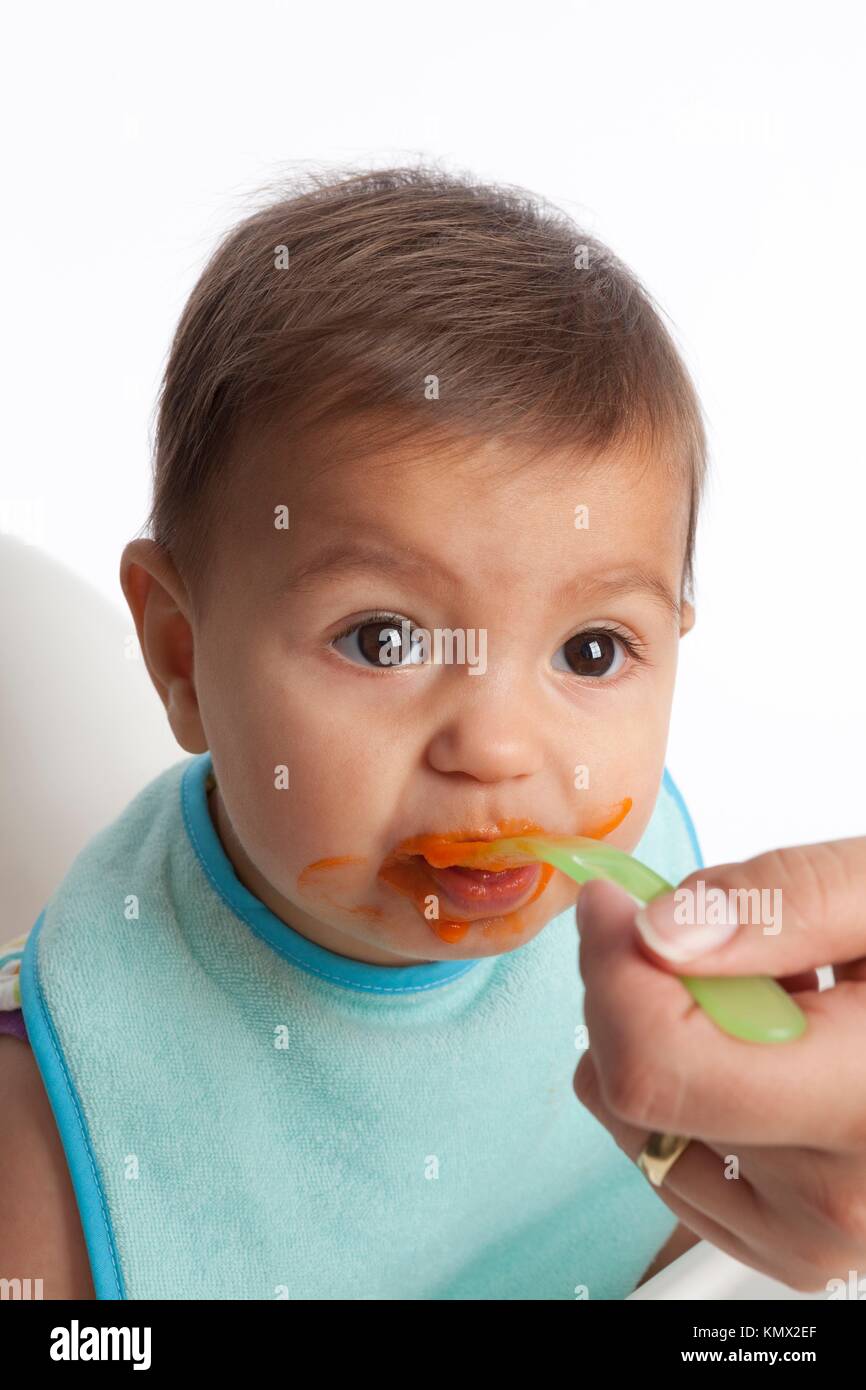 Baby girl is eating carrots with a spoon Stock Photo Alamy