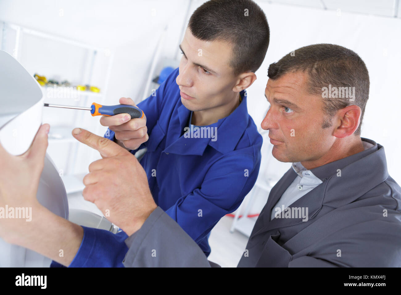 apprentice fixing something with the help of his teacher Stock Photo ...