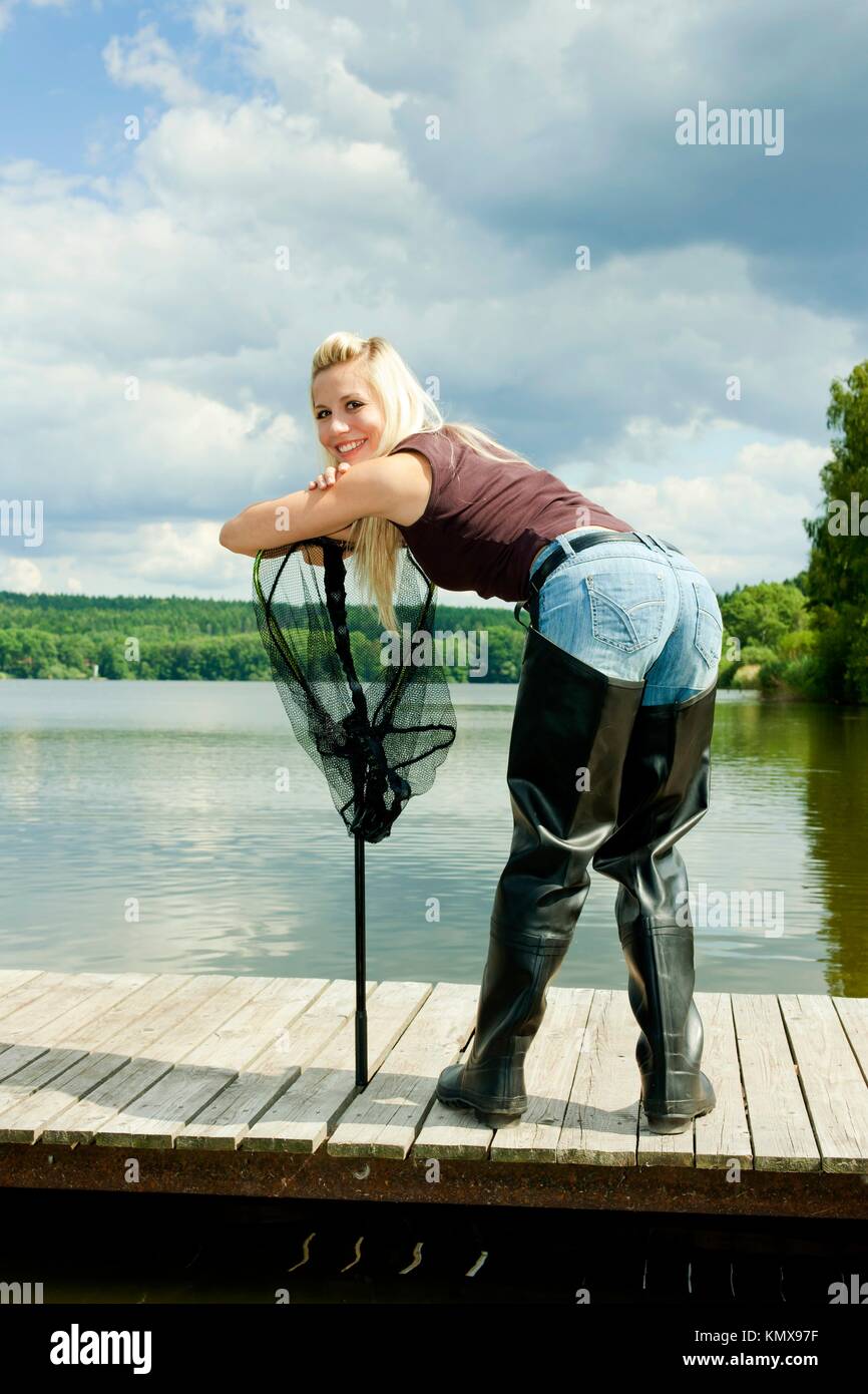fishing woman with landing net standing on pier Stock Photo - Alamy