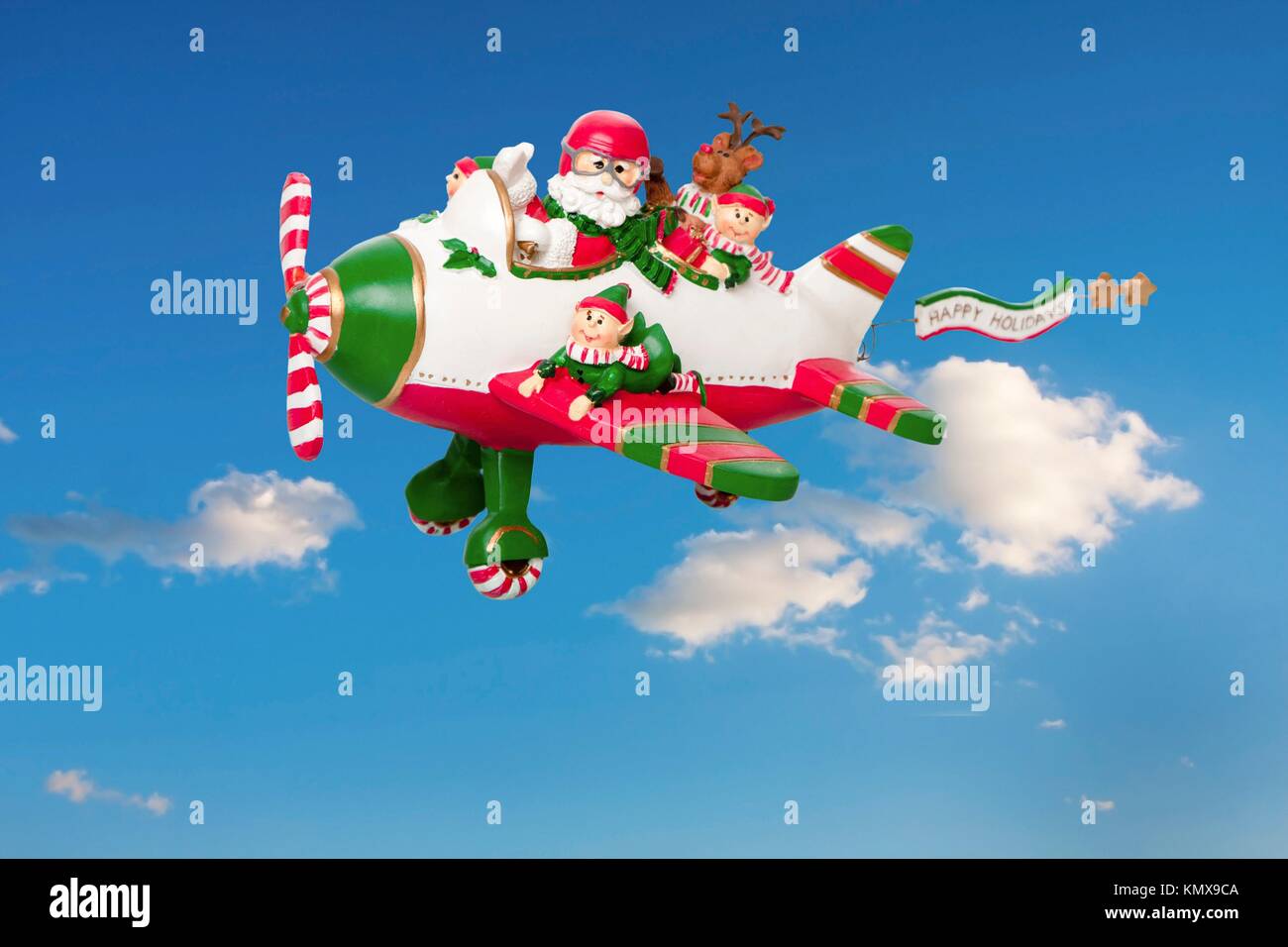 Santa Claus flying his airplane with Happy Holidays banner in the sky with his elves and
