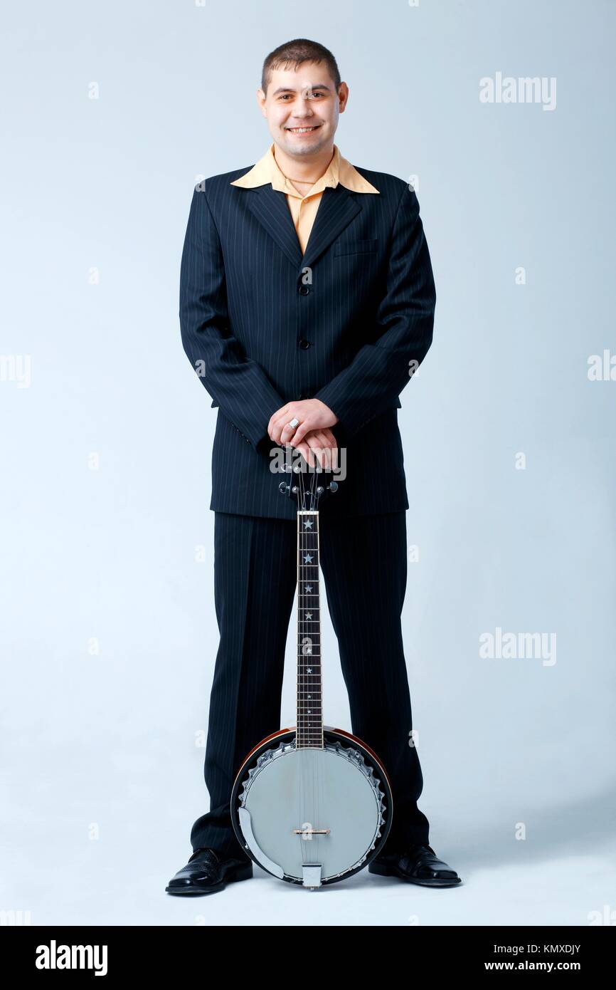 Man in dark suit standing with banjo, full length Stock Photo