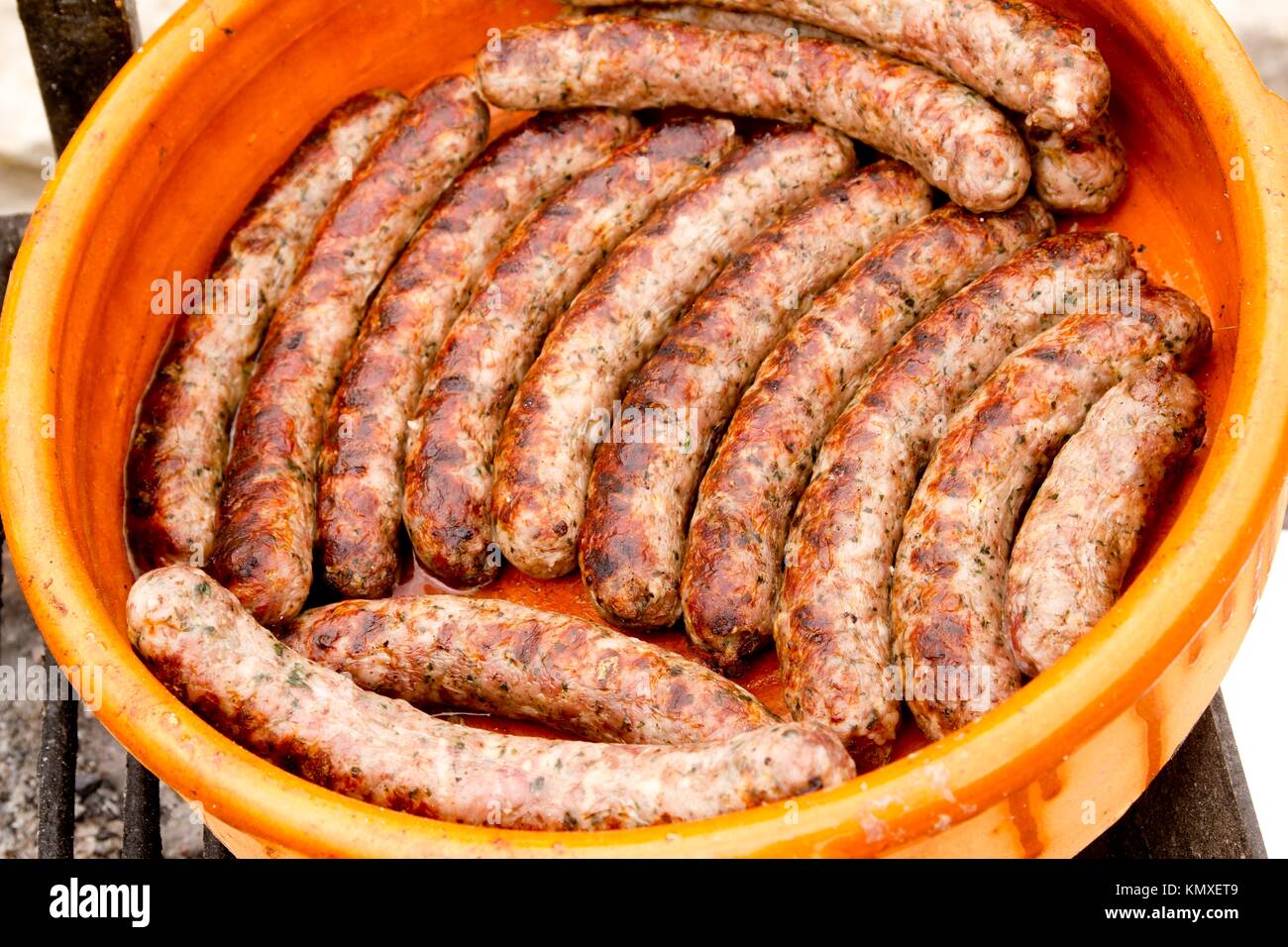 pork sausages in a row clay casserole Spain unhealthy food Stock Photo