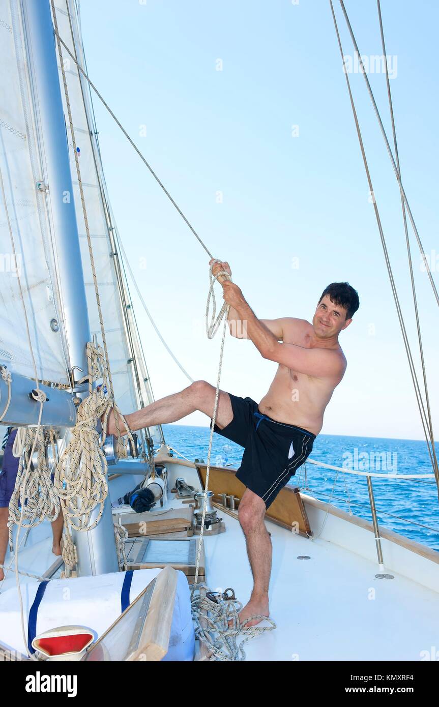 mature man smiling while hoisting the sail Stock Photo - Alamy