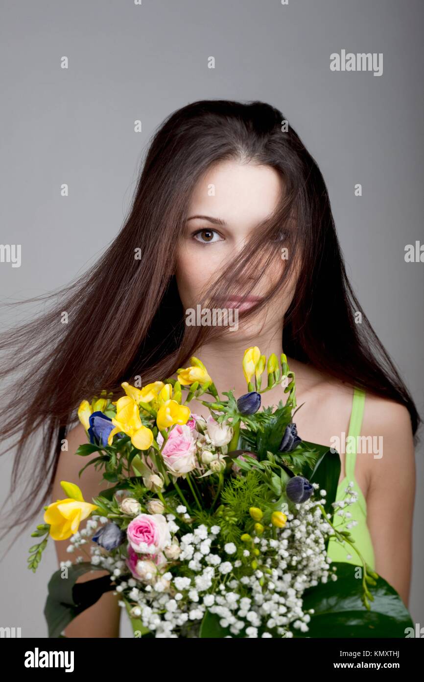 Beauty with a bunch of flowers, hair blowing in her face Stock Photo