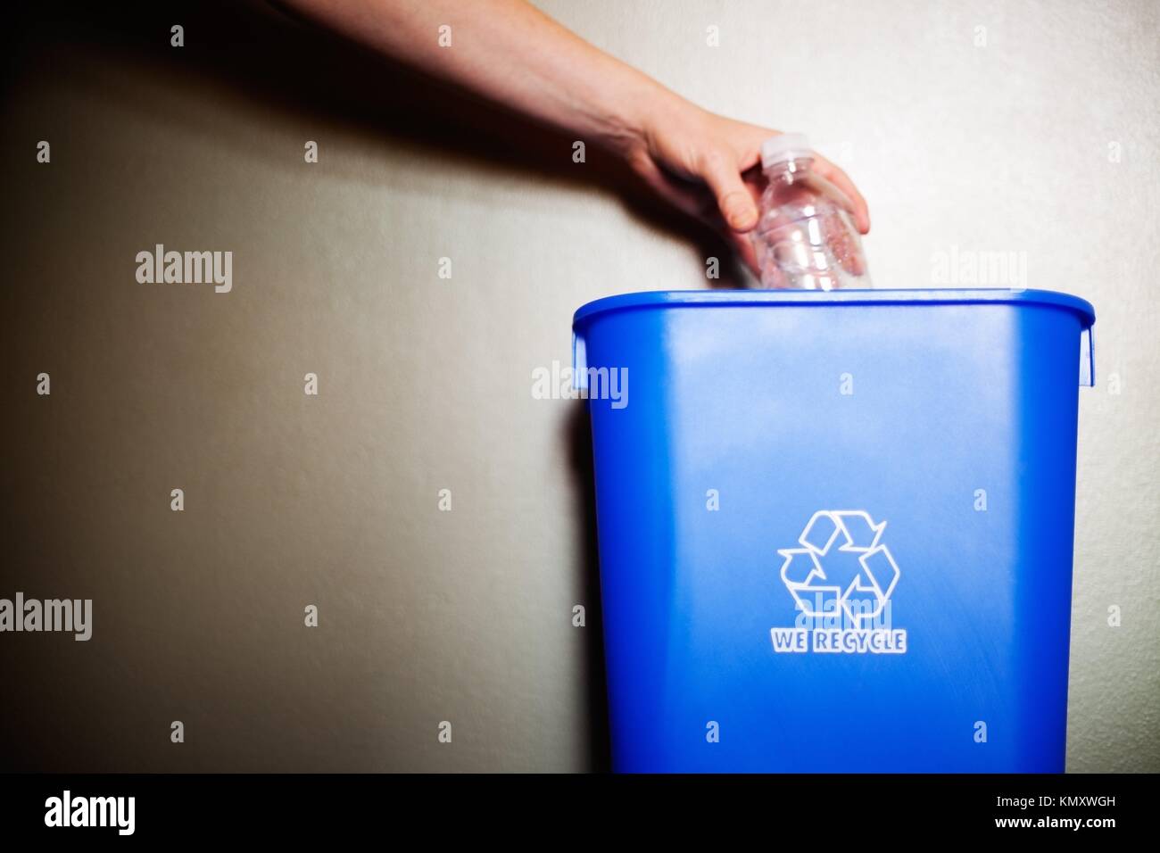 Woman´s arm dropping plastic bottling into recycling container Stock Photo