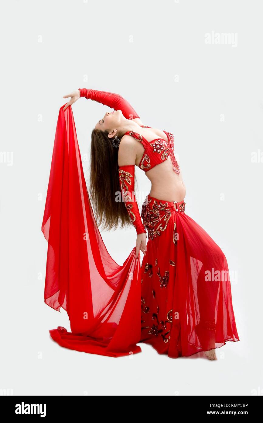 Beautiful belly dancer in red outfit holding veil hanging backward, isolated Stock Photo
