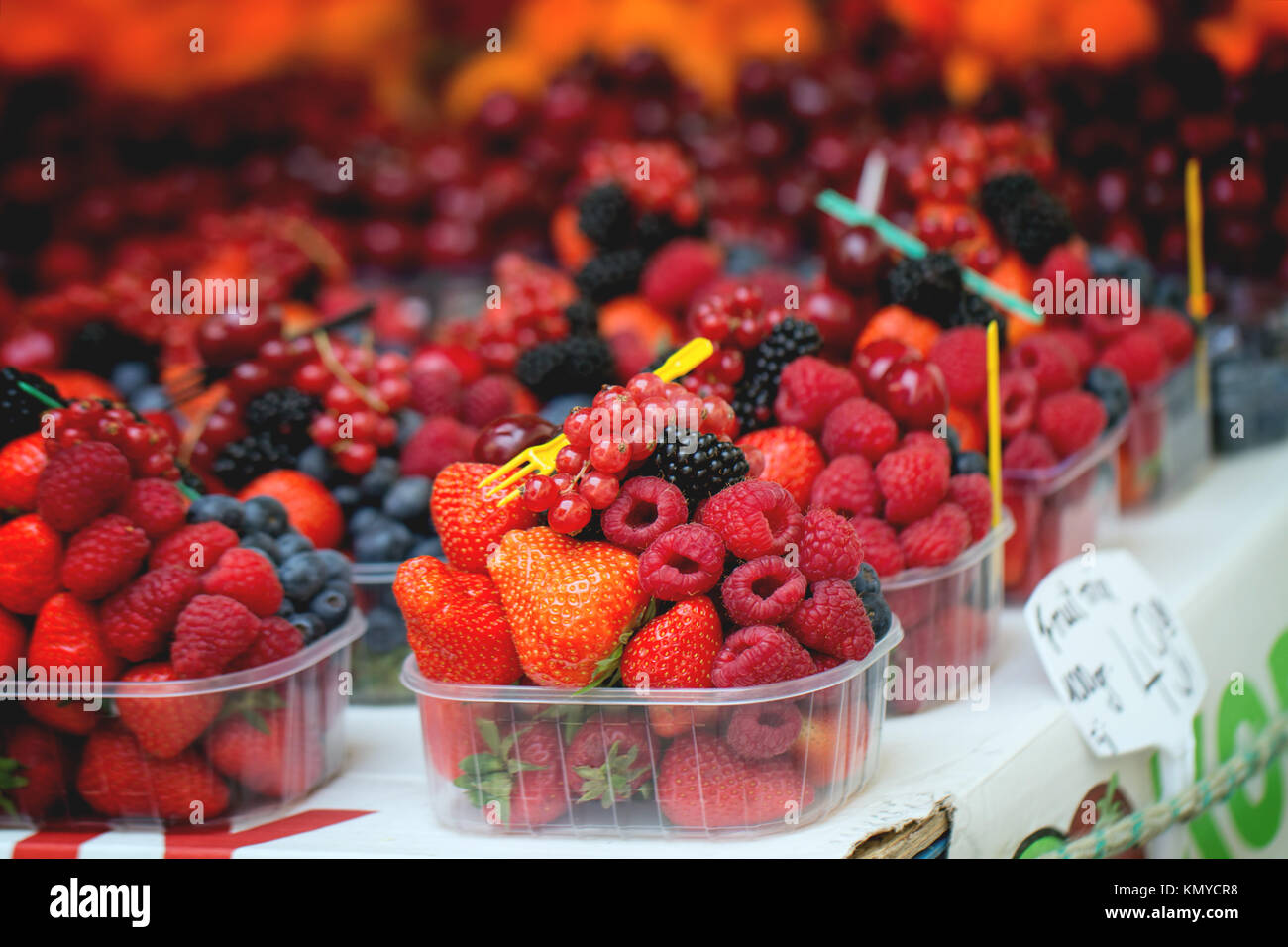 Mix of fresh ripe berries raspberry, strawberry, blackberry and blueberry in plastic boxes with disposable fork in market Stock Photo