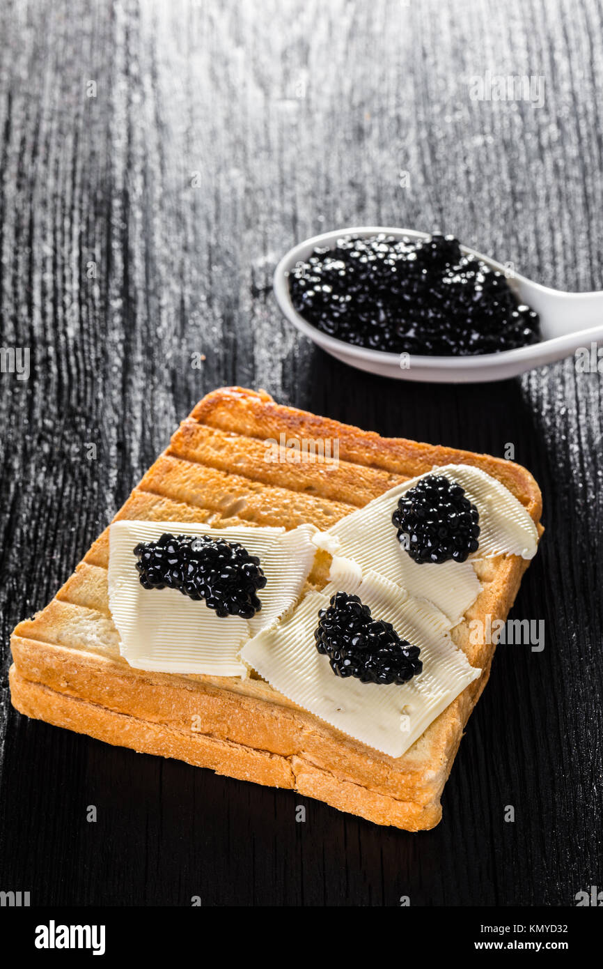 Toast with butter and caviar black wooden background Stock Photo - Alamy