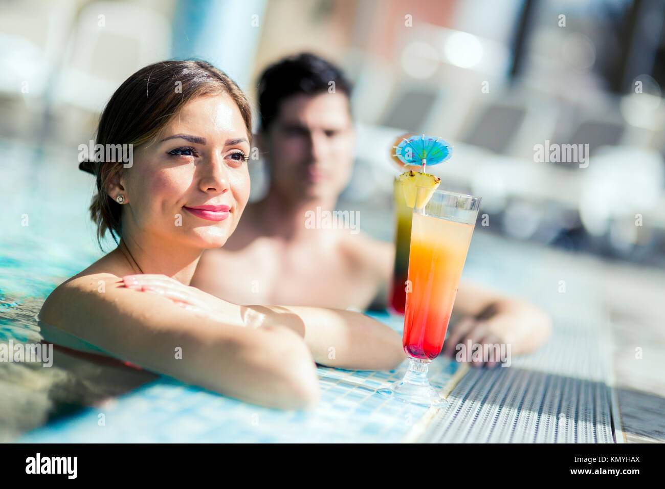 Young people drinking cocktails by the swimming pool and relaxin Stock