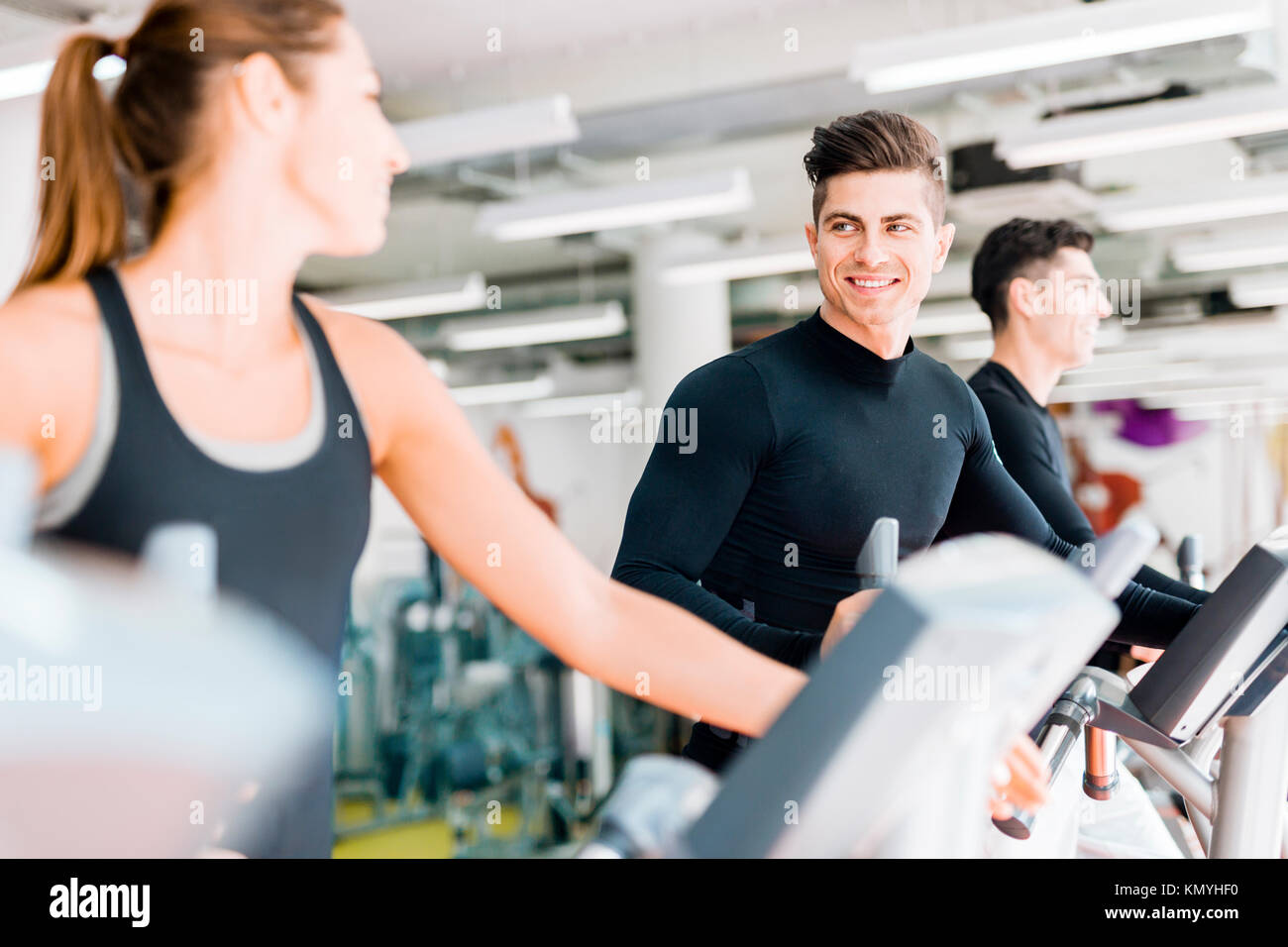 Handsome man and beautiful young woman using a stepper in a gym Stock Photo