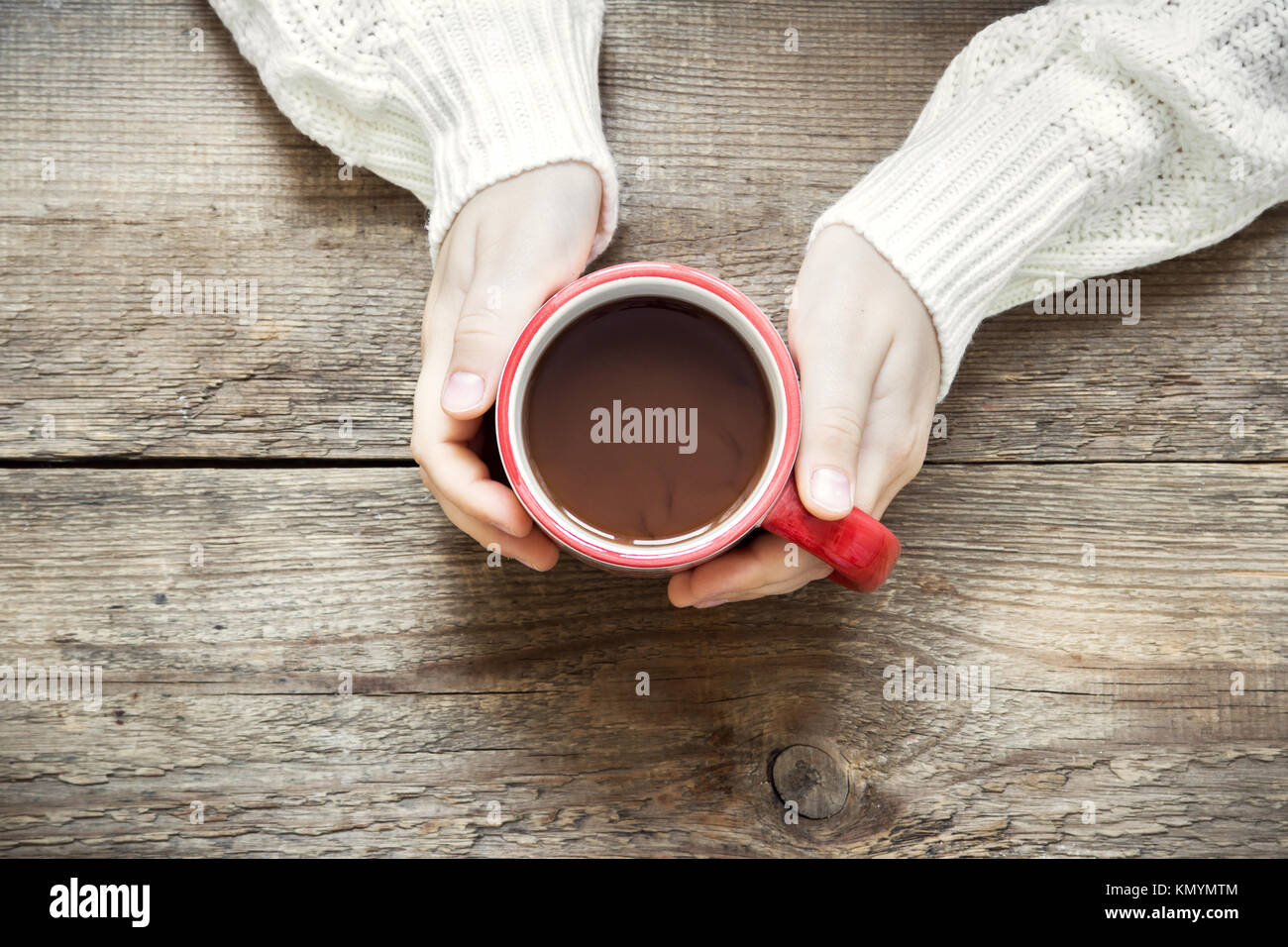 Female hands holding red mug of hot chocolate (coffee) on rustic wooden background with copy space Stock Photo