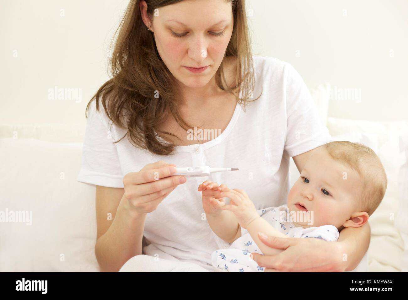 Mother taking her sick baby´s temperature with a thermometer Stock