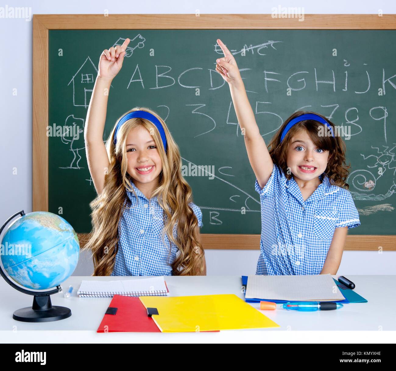 clever students in classroom raising hand with blackboard background Stock  Photo - Alamy