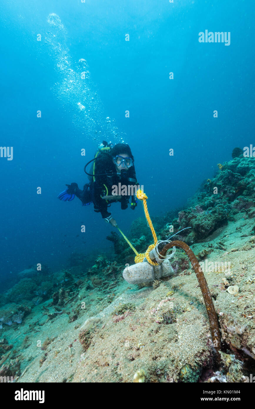 woman diver kolding a rope for safety stop in strong