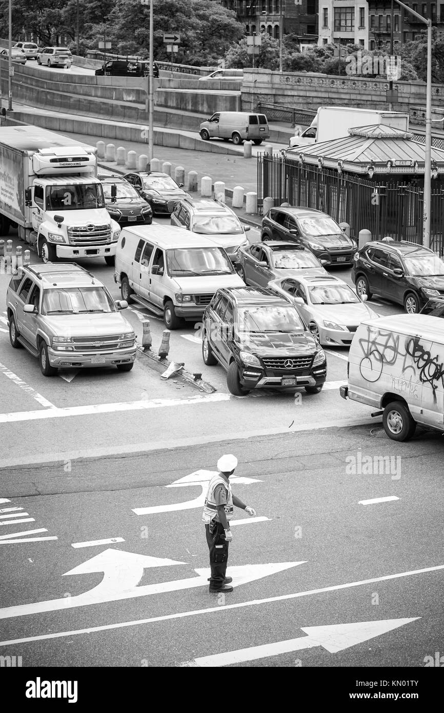 New York, USA - May 26, 2017: Police officer stands in the middle of the intersection and regulates traffic in midtown Manhattan. Stock Photo