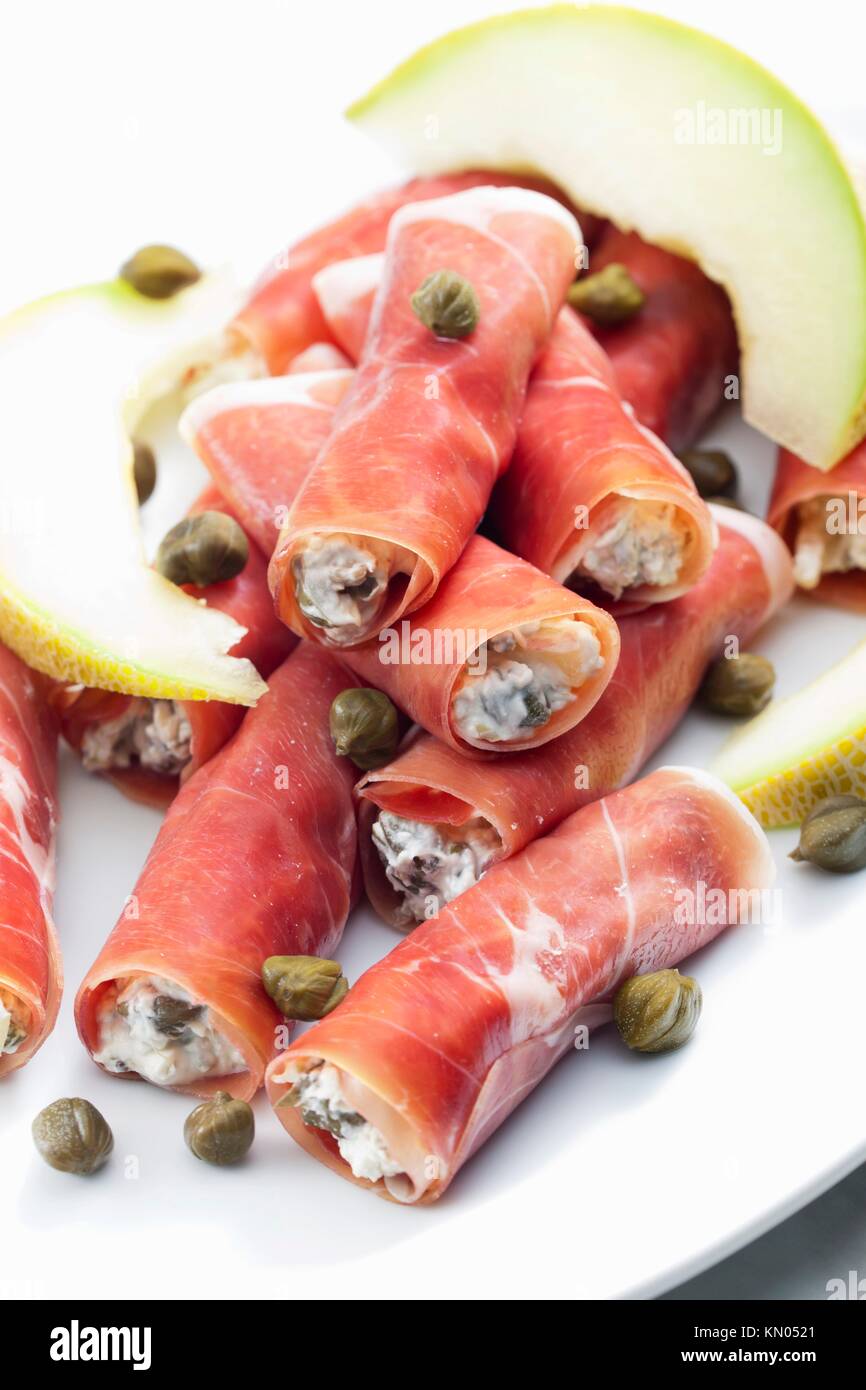 Parma ham rolls filled with cream cheese, Galia melon and capers Stock