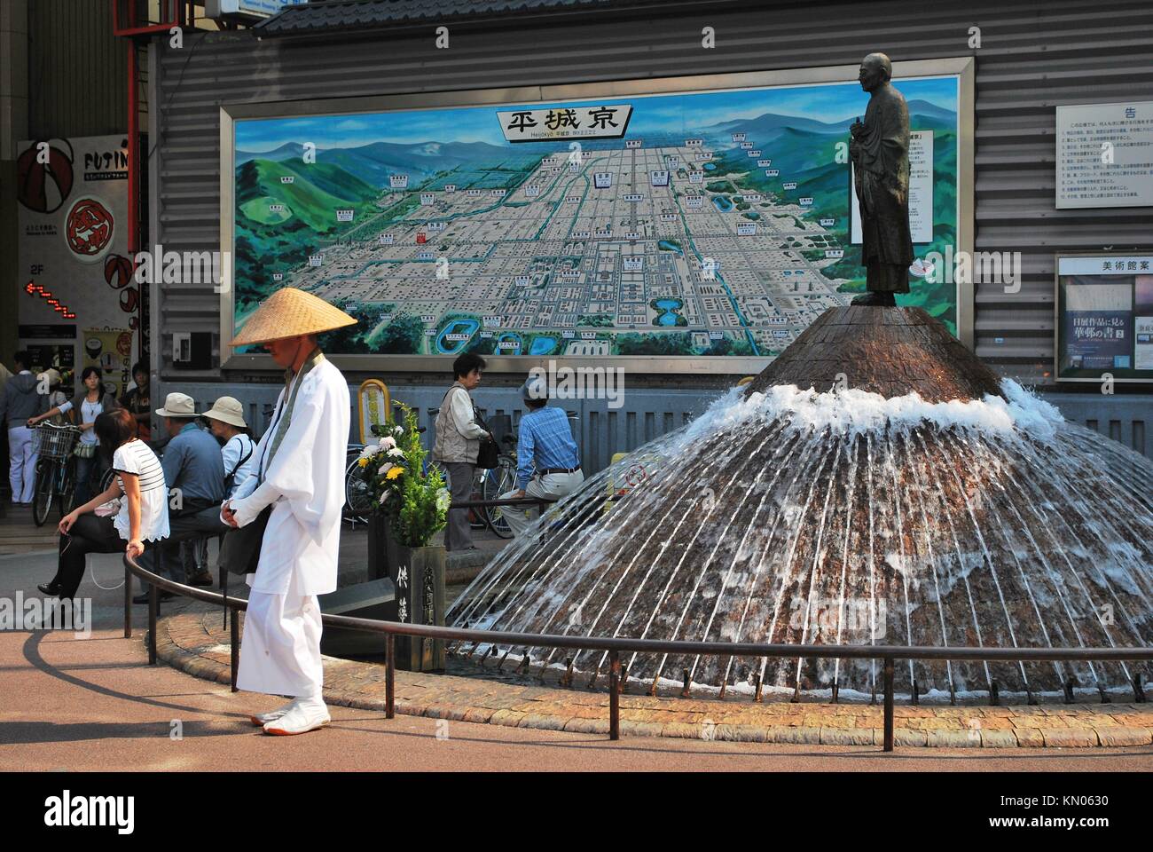 Taken at a clearing outside Nara station on the Kentetsu line in Japan. A monk stands at the fountain asking for alms. Stock Photo