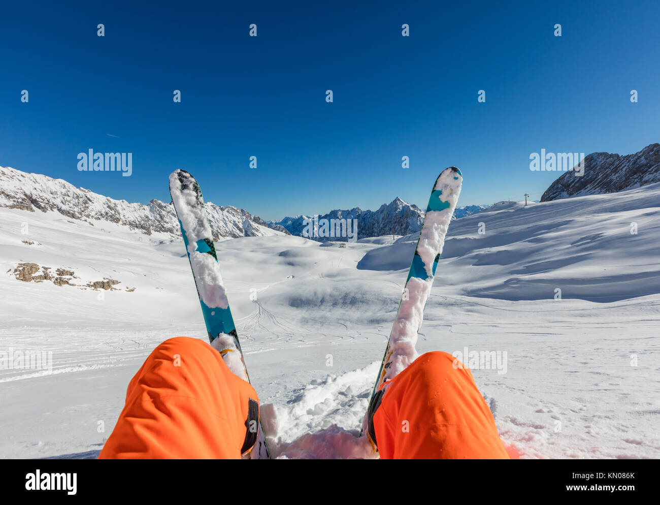 Skier sitting in powder snow, watching Alpine scenery. Winter activities and sports, outdoor scenery Stock Photo