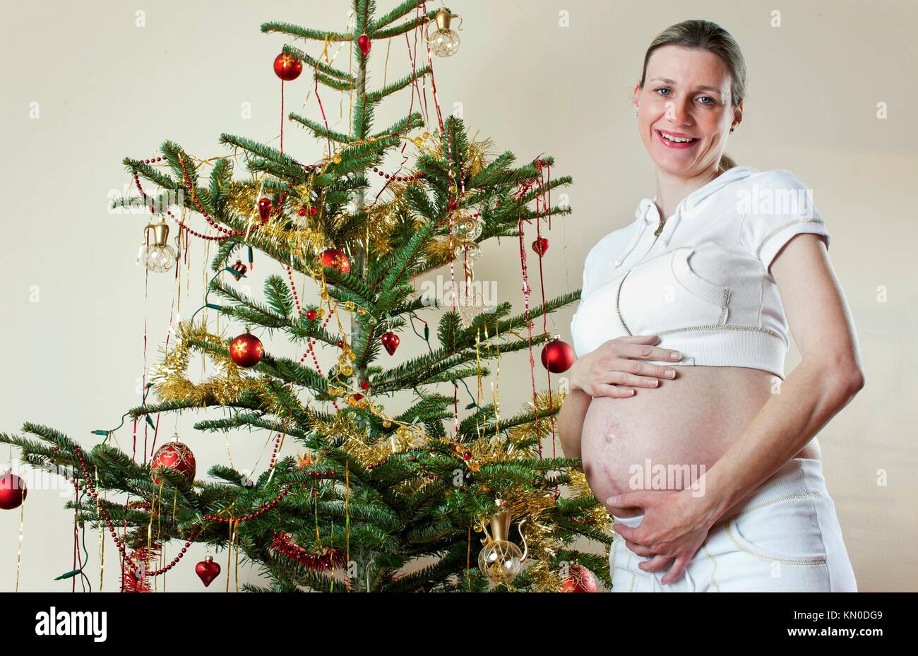 portrait of pregnant woman standing by Christmas tree Stock Photo - Alamy