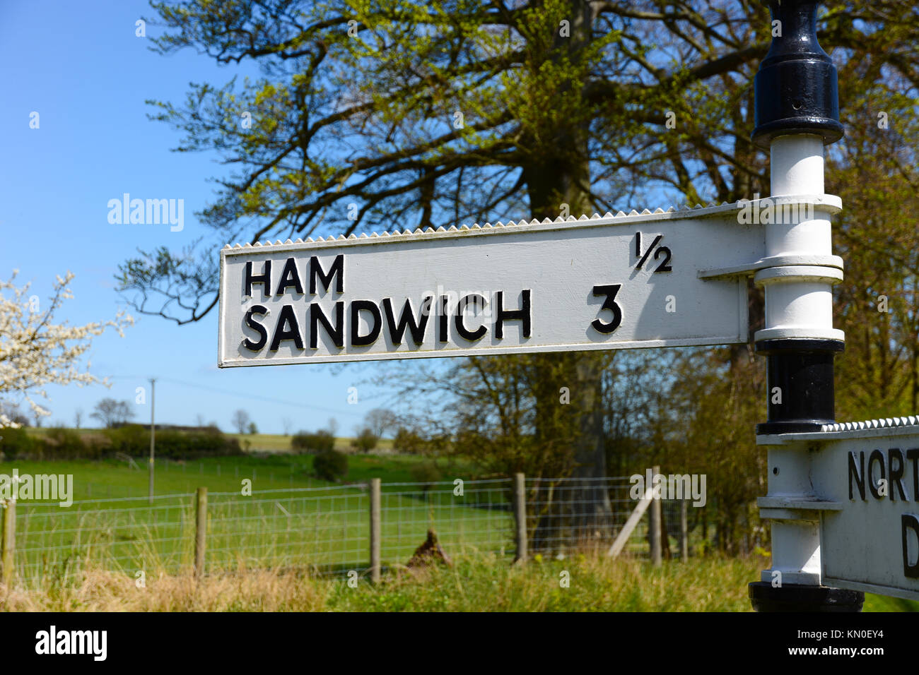 Amusing funny old fashioned signpost for Ham Sandwich in Kent, England with blue sky, sunshine and green field behind Stock Photo