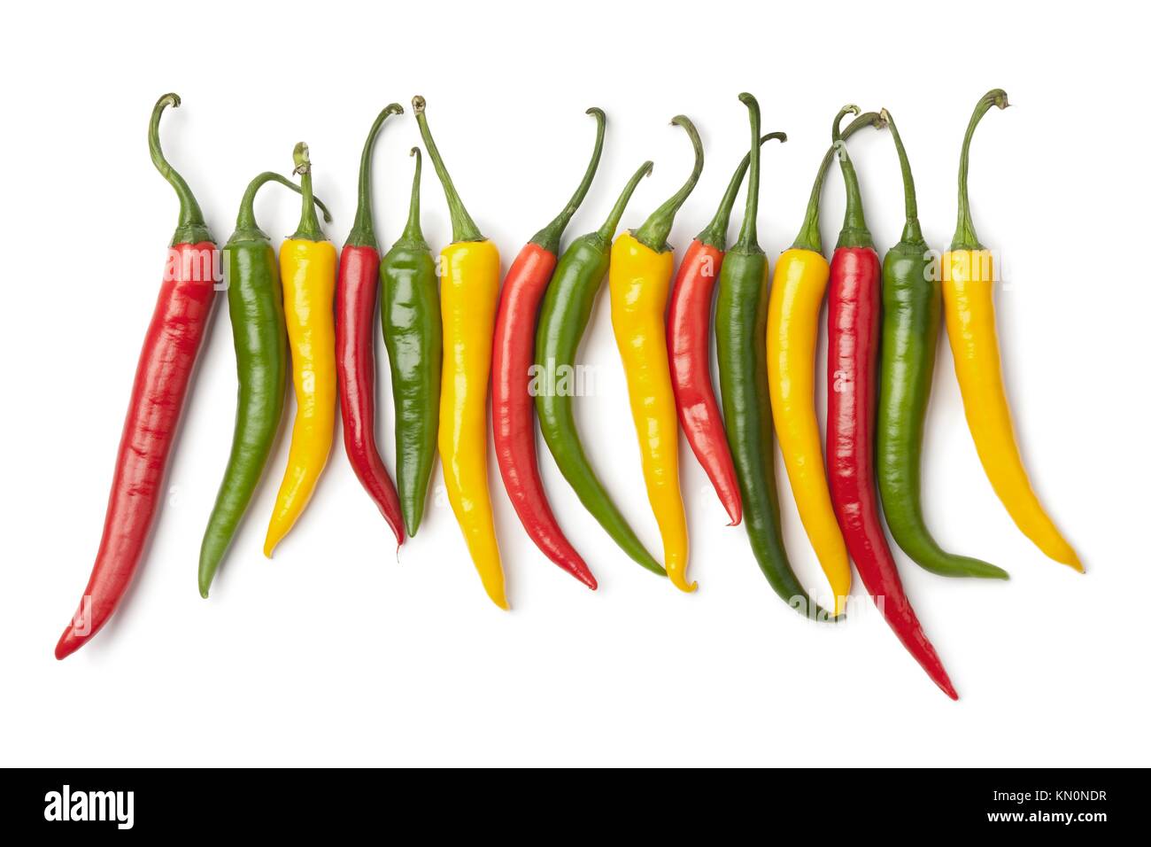 Red, yellow and green chili peppers in a row on white background Stock