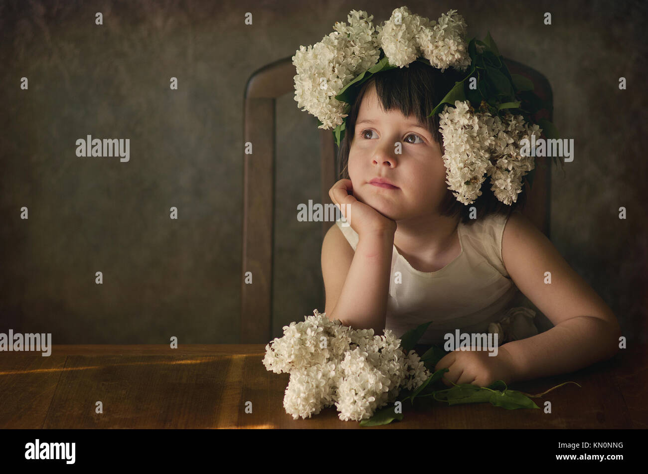 Studio portrait of beautiful girl 2-4 years with lilac flower garland on her head. Dreamy mood, creative look. Stock Photo