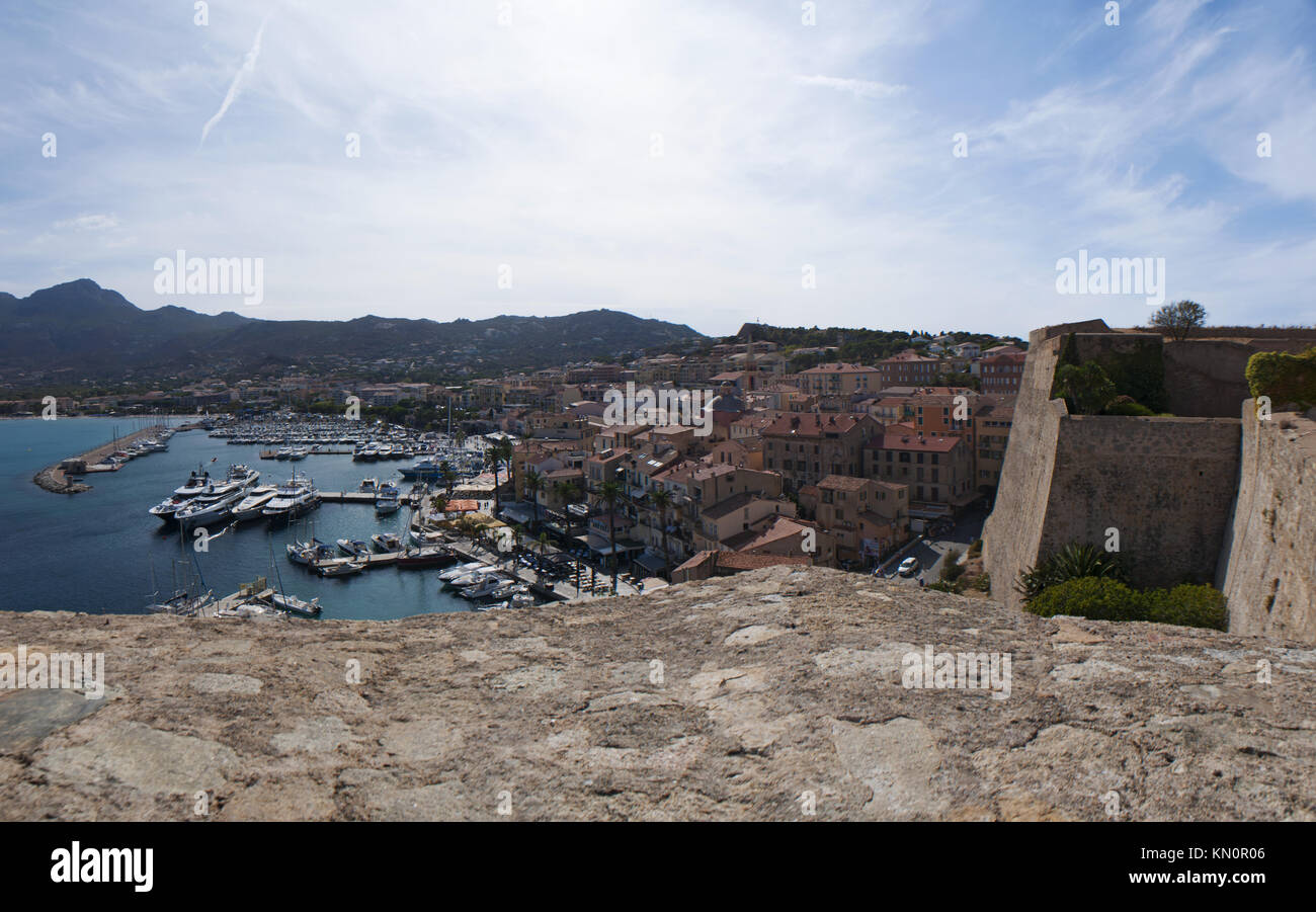 Corsica: Mediterranean Sea with boats in the marina and view of the skyline of Calvi seen from the ancient walls of the Citadel Stock Photo