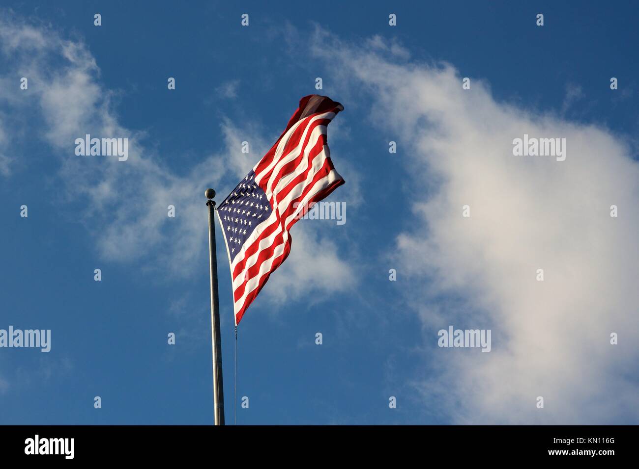 The United States´ stars and stripes streaming in the wind against a cloudy sky Stock Photo
