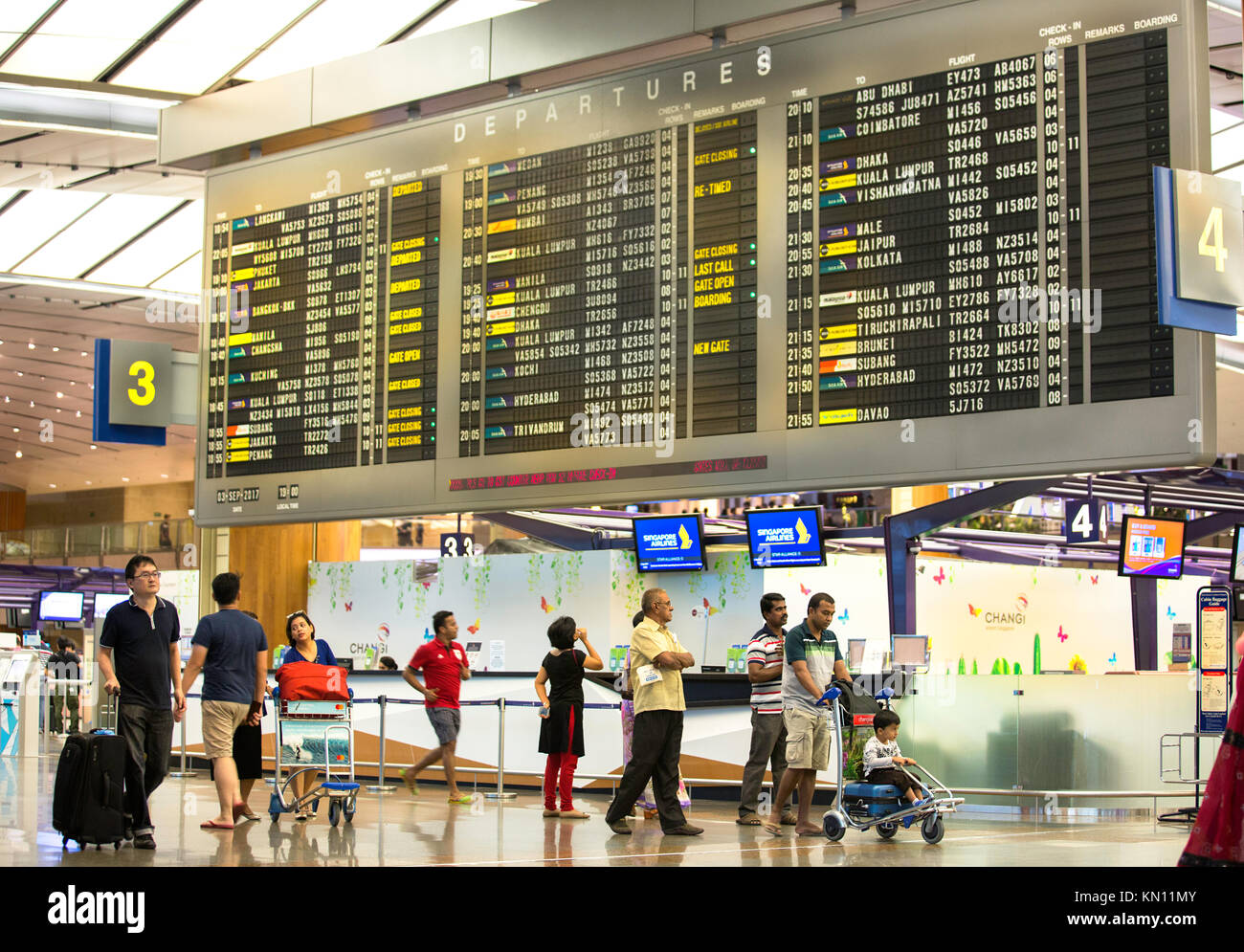 travellers checking flight timings in large screens,changi air port singapore Stock Photo