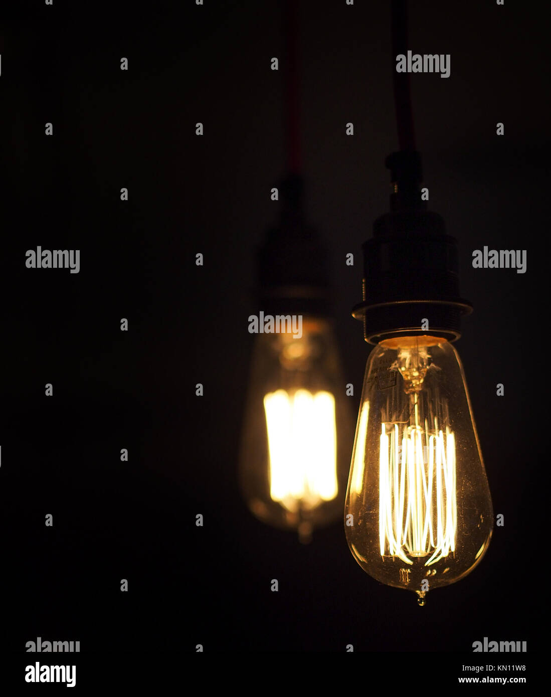 Two isolated vintage style glowing light bulbs one is unfocused closeup