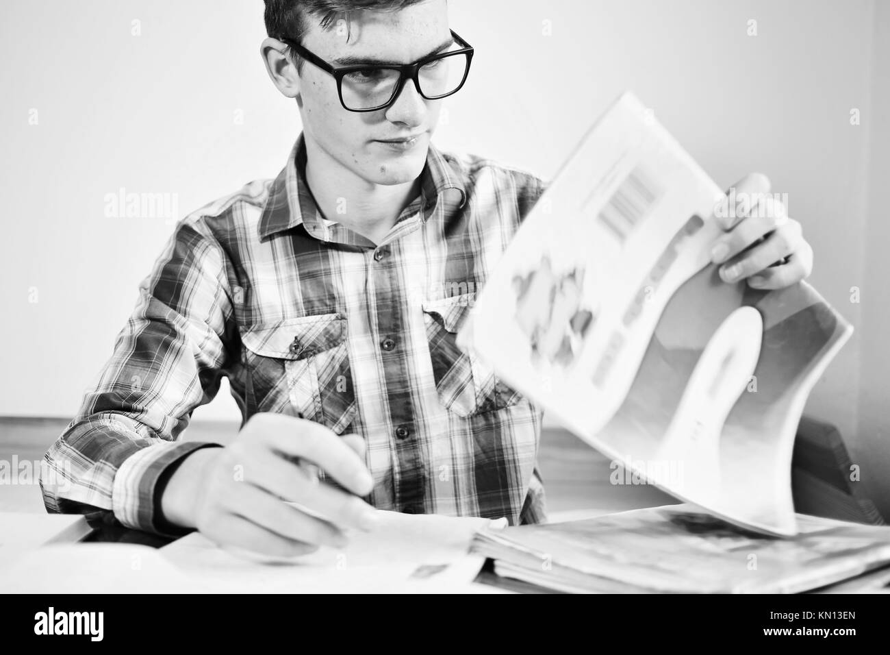 The student with glasses, teenager does a homework, he works from a book. learning a concept. Stock Photo