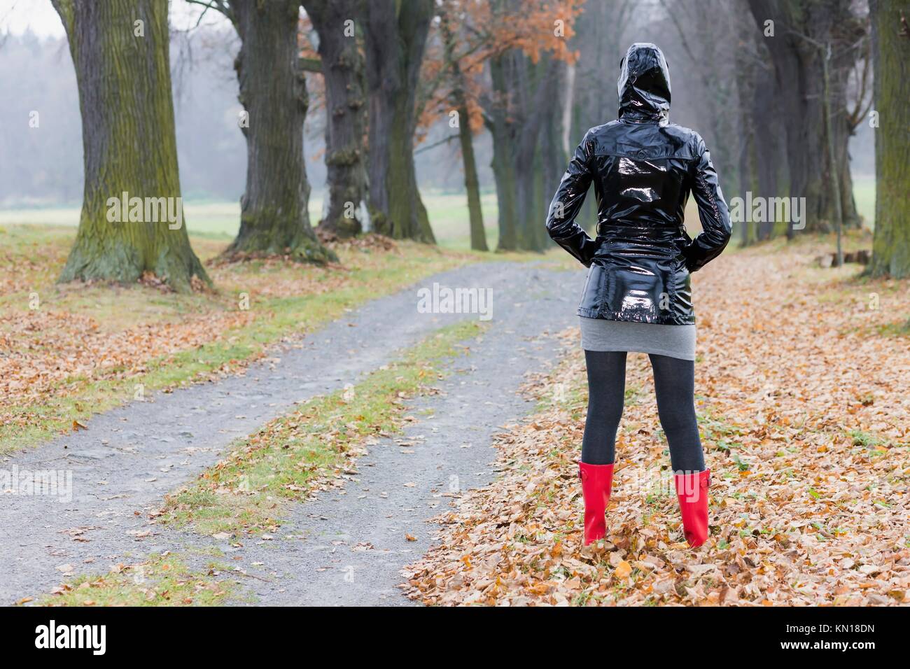 woman wearing rubber boots in autumnal alley Stock Photo Alamy