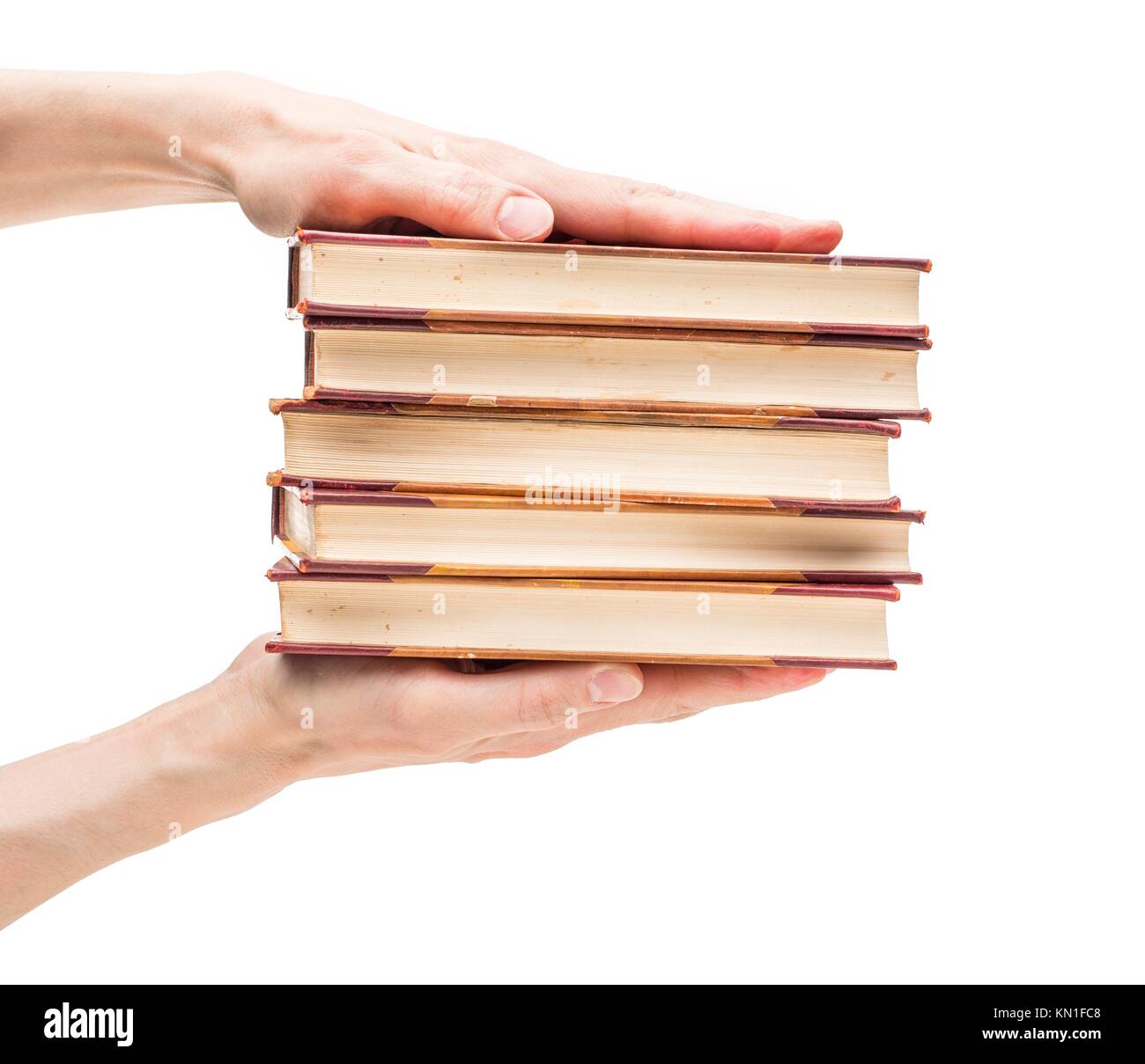 Closeup on white background of male hands holding stack of old vintage books. Stock Photo