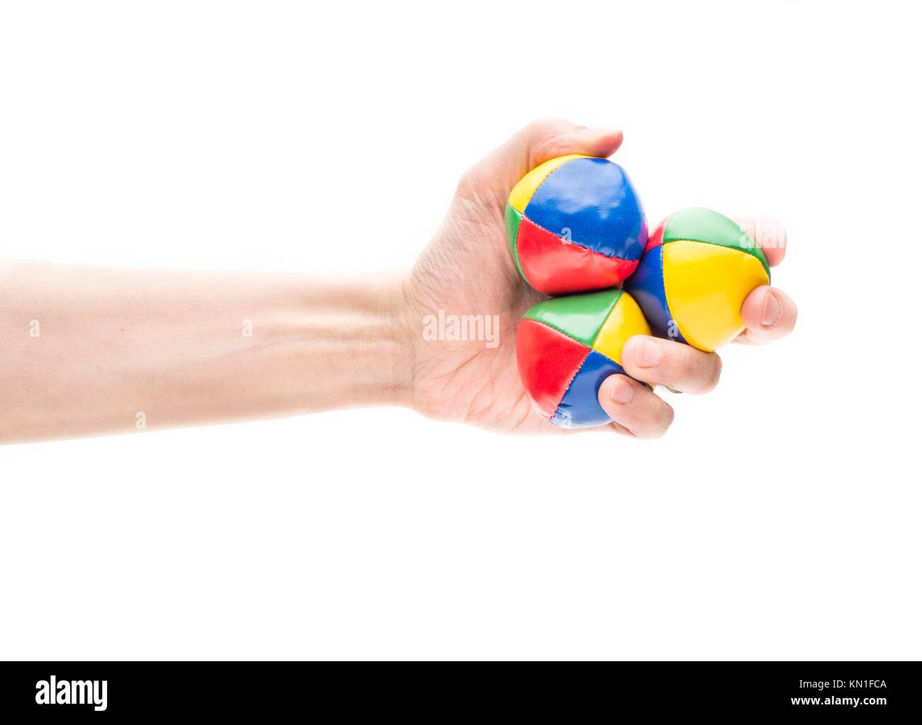 Closeup on white background of male hand holding three colorful juggling balls. Stock Photo