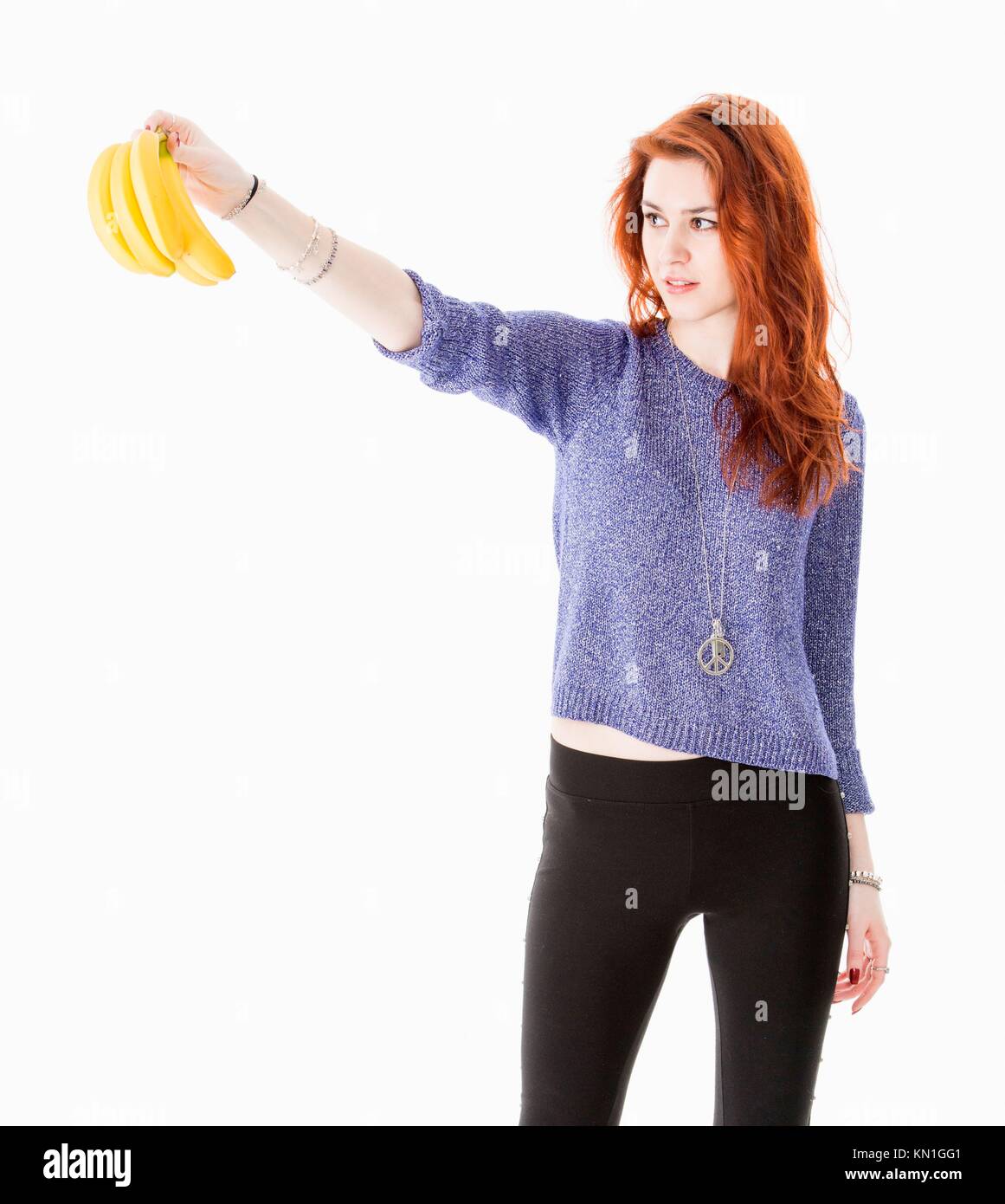 Young natural looking woman holding a bunch of bananas. Stock Photo