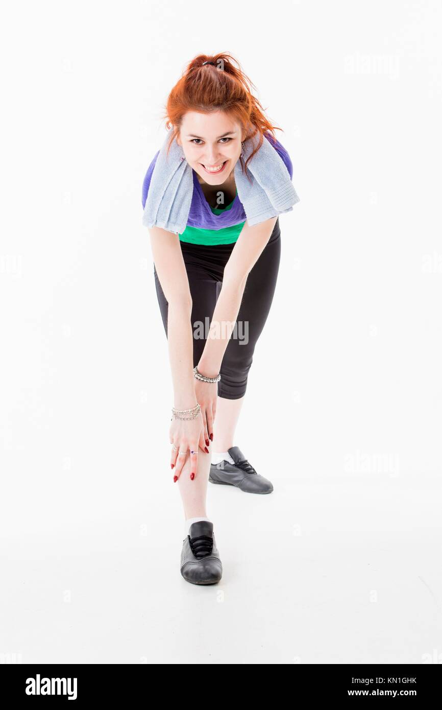 Studio portrait of attractive young woman with red hair working out and stretching. Stock Photo