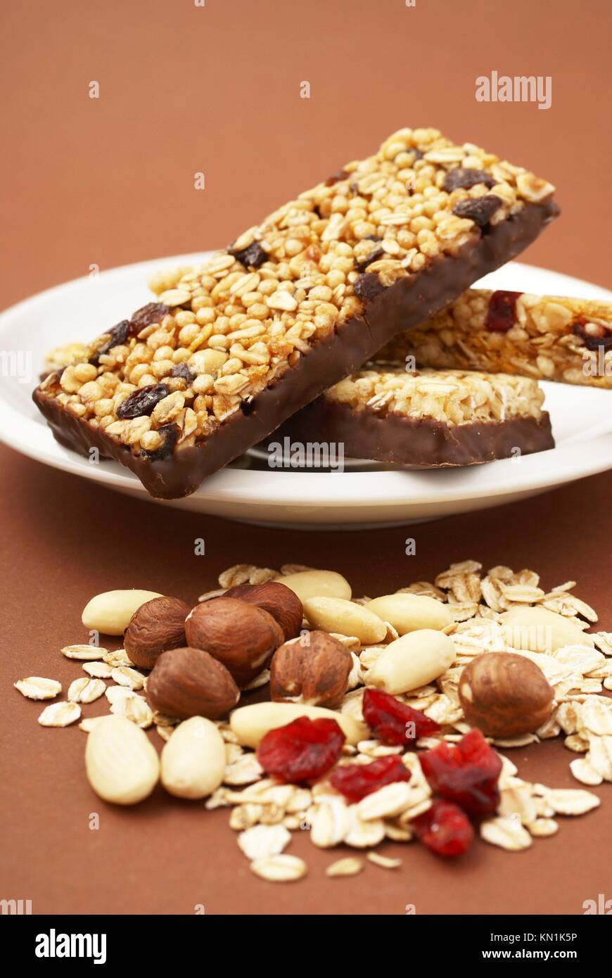 Granola bar, almonds, nuts, dry cranberries, oat flakes and glass of milk. Stock Photo