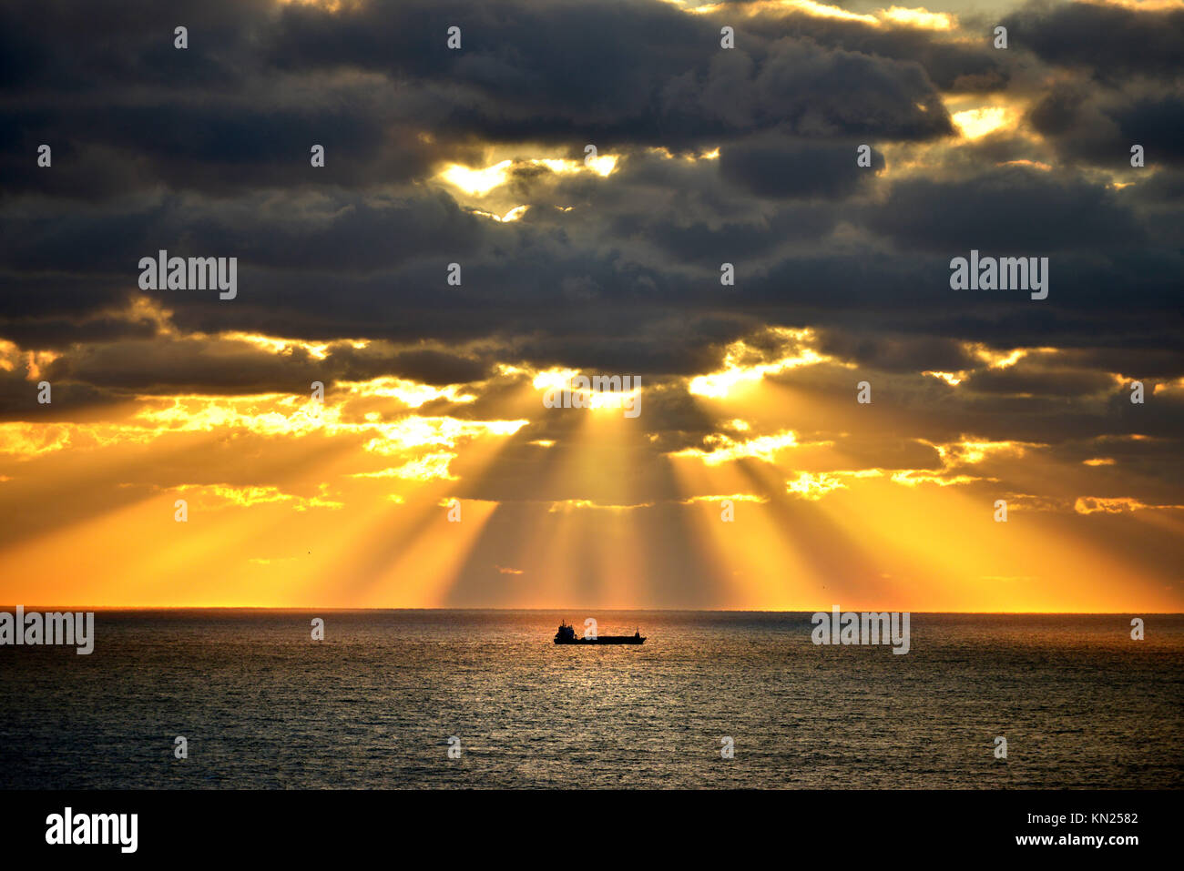 Container ship lit by rays of the setting sun, English channel. Stock Photo