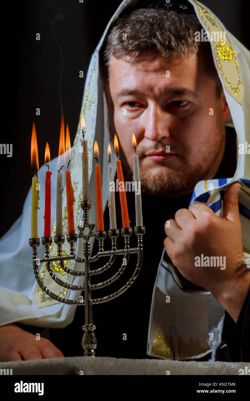 man hand lighting candles in menorah on table served for Hanukkah Stock